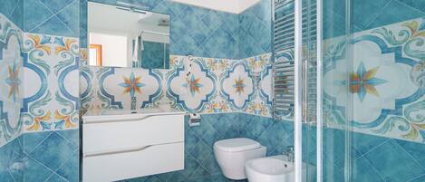 Ein Badezimmer mit blauen Fliesen, einem weißen Waschbecken und zwei Toiletten.