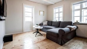 Un salon chaleureux avec un canapé gris, une petite table blanche et un plancher en bois.