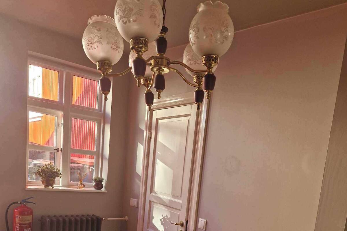 Un coin repas avec une table ronde en bois, des chaises noires et un lustre orné de plusieurs globes.
