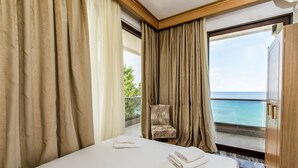Een hotelkamer met een bed, een stoel en uitzicht op zee.