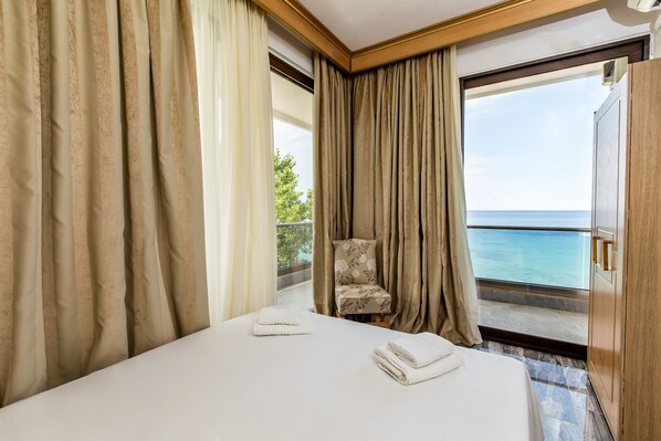 Habitación de hotel con cama, una silla y vista al mar.