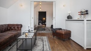 Un salón moderno con un sofá de cuero, una mesa de centro de vidrio y una alfombra estampada.
