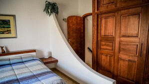 Ein Schlafzimmer mit einem Bett, einem Holzschrank und einem kleinen Nachttisch.