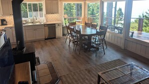 A kitchen with white cabinets, a dishwasher, and a dining area with a wooden table and chairs.