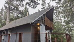 A cabin with a wooden deck, a covered porch, and a chimney.