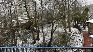 Paisaje nevado con árboles desnudos y un edificio al fondo.