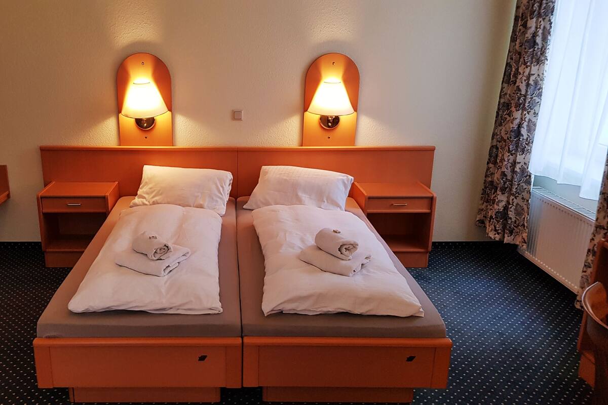 Una cama doble con dos mesitas de noche, cada una con una lámpara, en una habitación de hotel.