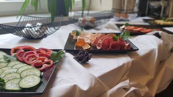 A buffet table with various food items including sliced cucumbers, tomatoes, and meat.