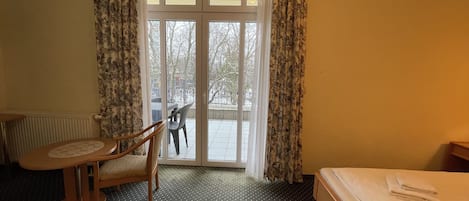 Habitación de hotel con cama, una silla, una mesita y vistas a un paisaje nevado a través de una puerta de cristal.