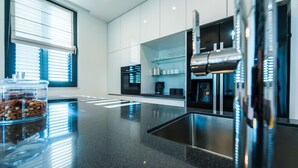 Cozinha moderna com bancada preta, eletrodomésticos de aço inoxidável e um recipiente de vidro com nozes.