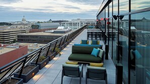 Une terrasse sur le toit avec des sièges en plein air, une vue sur le Capitole et, en arrière-plan, un bâtiment moderne en verre.