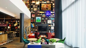 Ein moderner Lounge-Bereich mit einer großen Wand voller gerahmter Fotos und Kunstwerken, einem Flachbildfernseher und bequemen Sitzgelegenheiten.