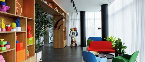 A modern interior with a wooden bookshelf, colorful chairs, and a large window.