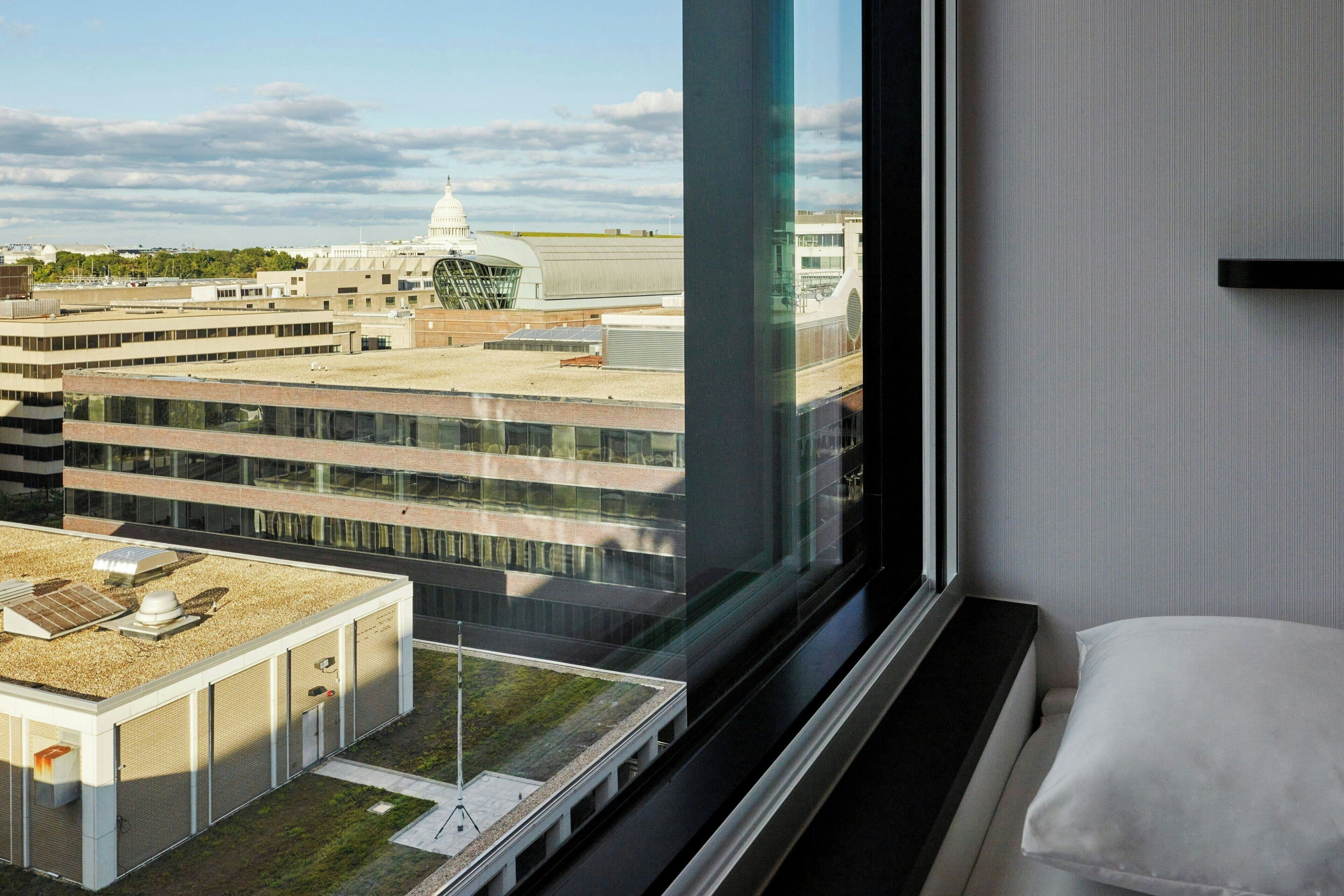 A hotel room with a large window offering a view of a modern building and a dome structure.