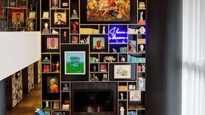 Ein modernes Wohnzimmer mit Kamin, roten Sofas, einem Bücherregal voller Gegenstände und einem großen Gemälde über dem Kamin.