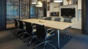 A conference room with a long table, six chairs, and three pendant lights.
