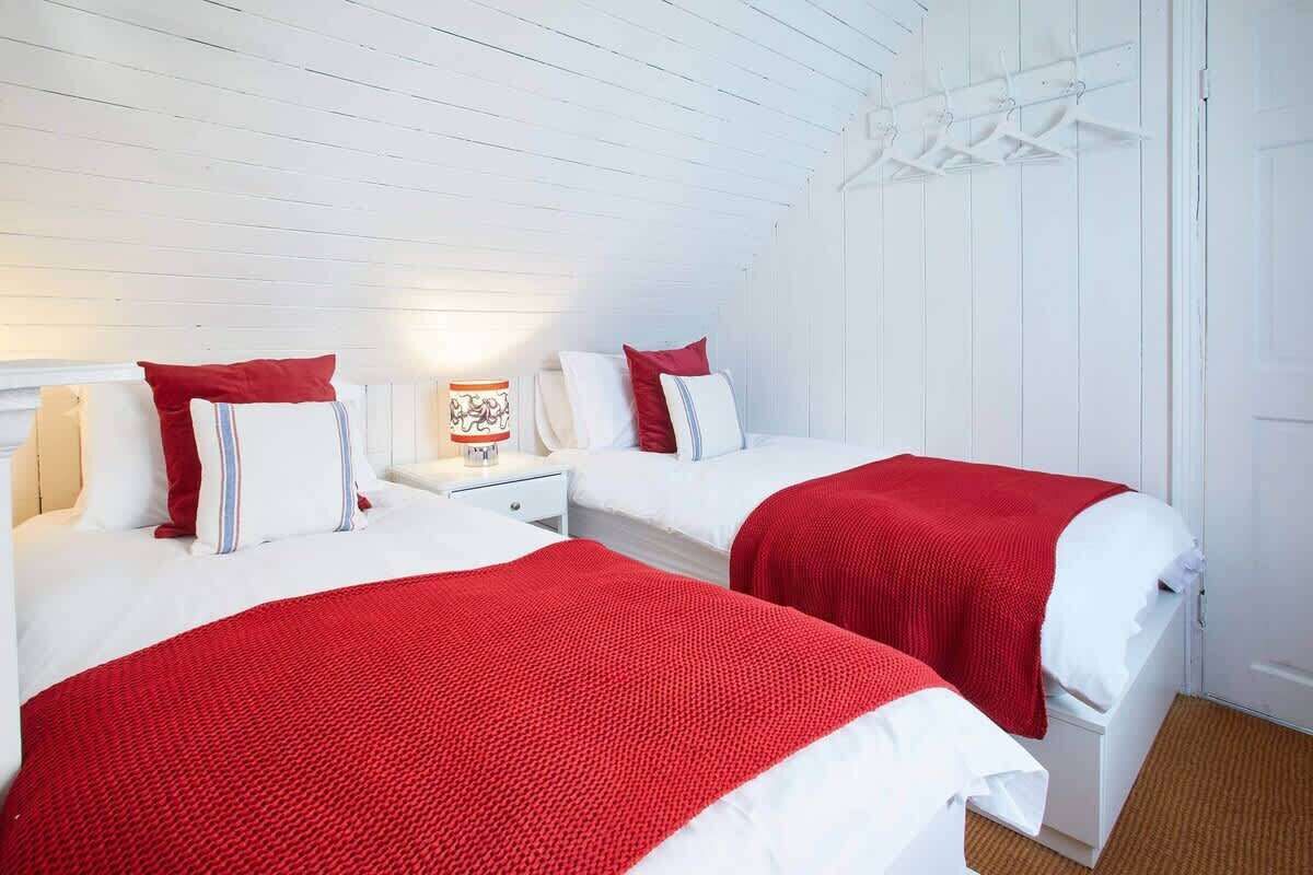 Une chambre avec deux lits, des murs blancs et un plafond en bois.