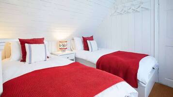 Une chambre avec deux lits, des murs blancs et un plafond en bois.