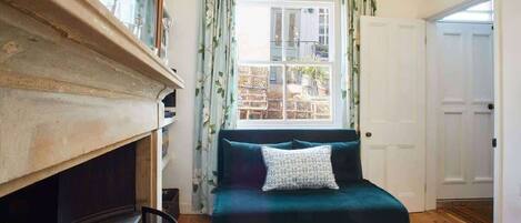 Un salon chaleureux avec une cheminée, un canapé de couleur turquoise et une porte blanche.