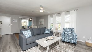 A living room with a gray sofa, a patterned armchair, a coffee table, and a ceiling fan.
