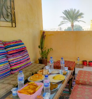 Un comedor con una mesa dispuesta para una comida, incluyendo platos de comida, una cesta de papas fritas y varias botellas de agua.