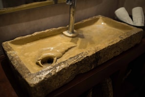 A stone sink with a faucet and a basin.