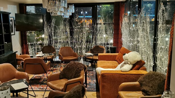 Un espace salon confortable avec des canapés en cuir, un téléviseur et des éléments décoratifs tels qu’un ours et un raton laveur.