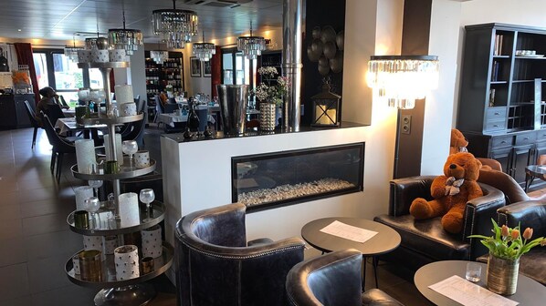 Una zona de bar con una estantería para vinos, una chimenea y un mullido osito de peluche sobre un sofá de cuero.