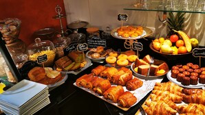 Un buffet proposant une variété de plats, notamment des pâtisseries, des fruits et des condiments.
