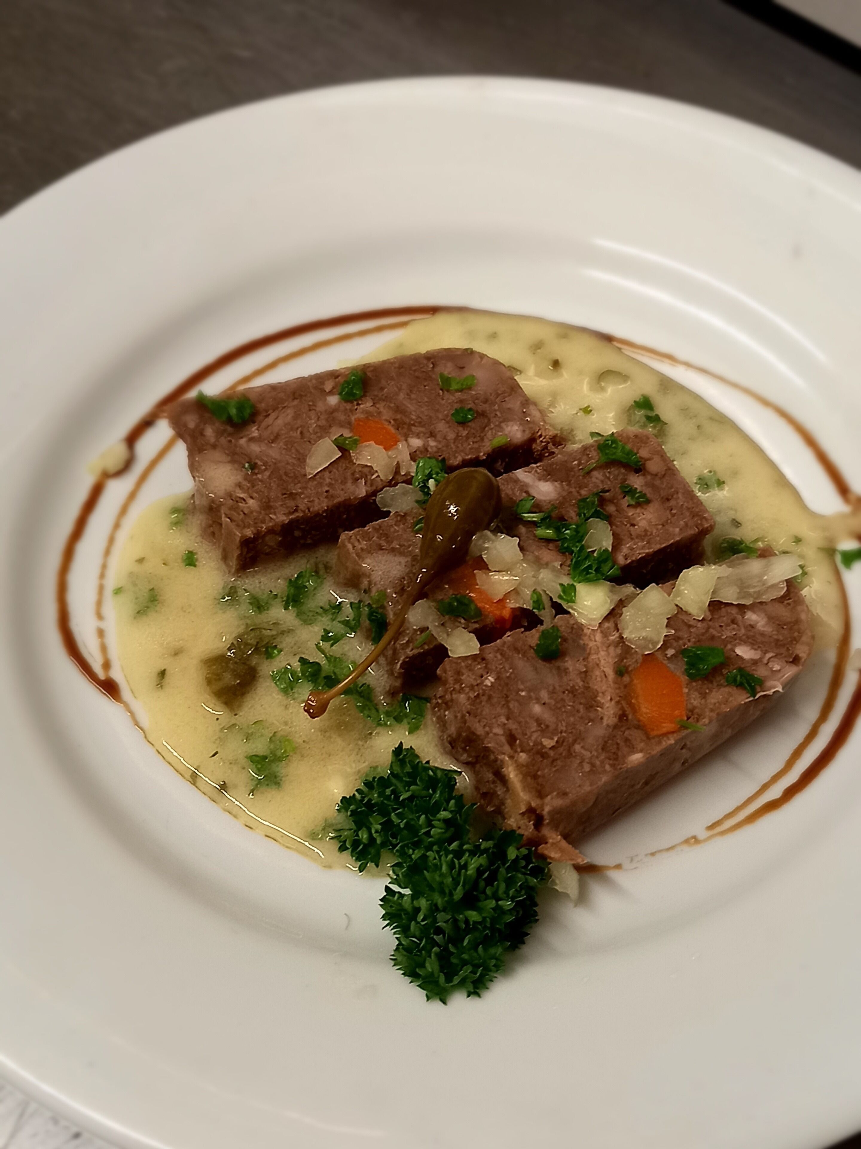 A plate of food with meat, vegetables, and a garnish.