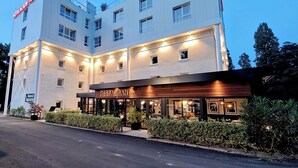 Un hôtel doté d’un restaurant au rez-de-chaussée, de plusieurs étages et d’une façade bien éclairée.