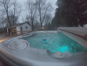 Een bubbelbad met een houten terras en een huis op de achtergrond.