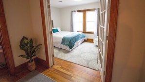 Um quarto com uma cama, um vaso de planta e uma janela com cortinas.