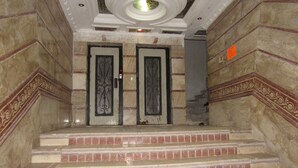 Un conjunto de escalones de mármol que conducen a un doble puerta con diseños intrincados, flanqueadas por paneles decorativos en la pared.