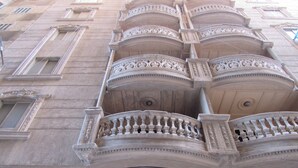 Un edificio con balcones ornamentados y un amplio ventanal al nivel de la calle.