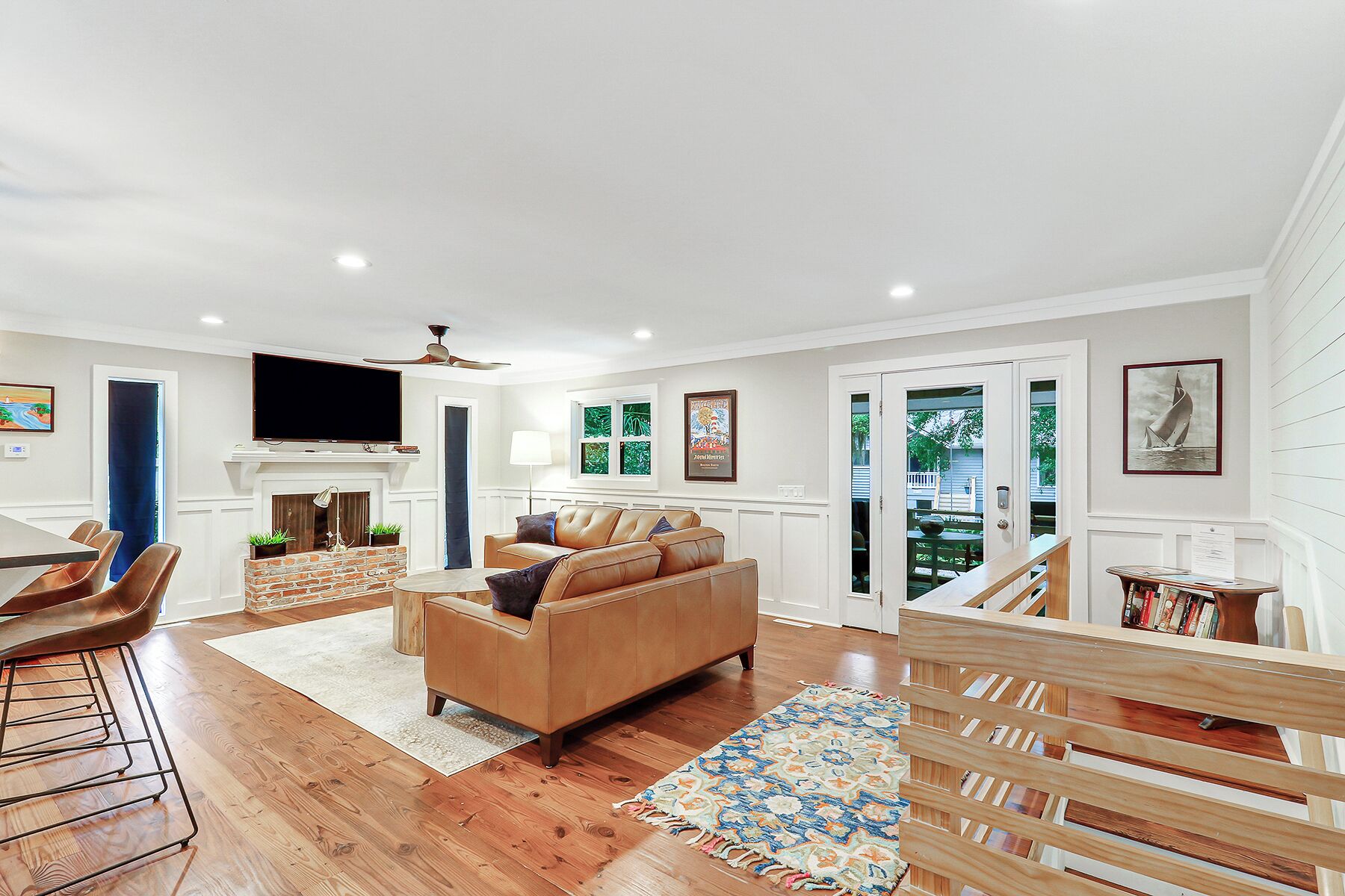 A spacious living room with a fireplace, leather sofa, and a dining area with a wooden table and chairs.