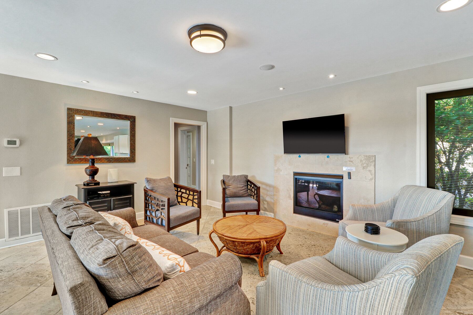 A spacious living room with a fireplace, comfortable seating, and a flat-screen TV mounted above it.