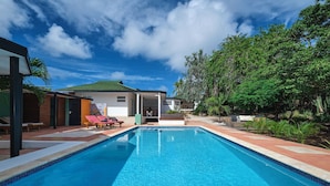 A swimming pool with lounge chairs and a covered seating area.