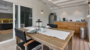 A modern kitchen with a wooden table set for dining, a refrigerator, and a microwave.