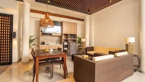 A modern kitchen with a dining area, featuring a wooden dining table, wicker furniture, and pendant lighting.