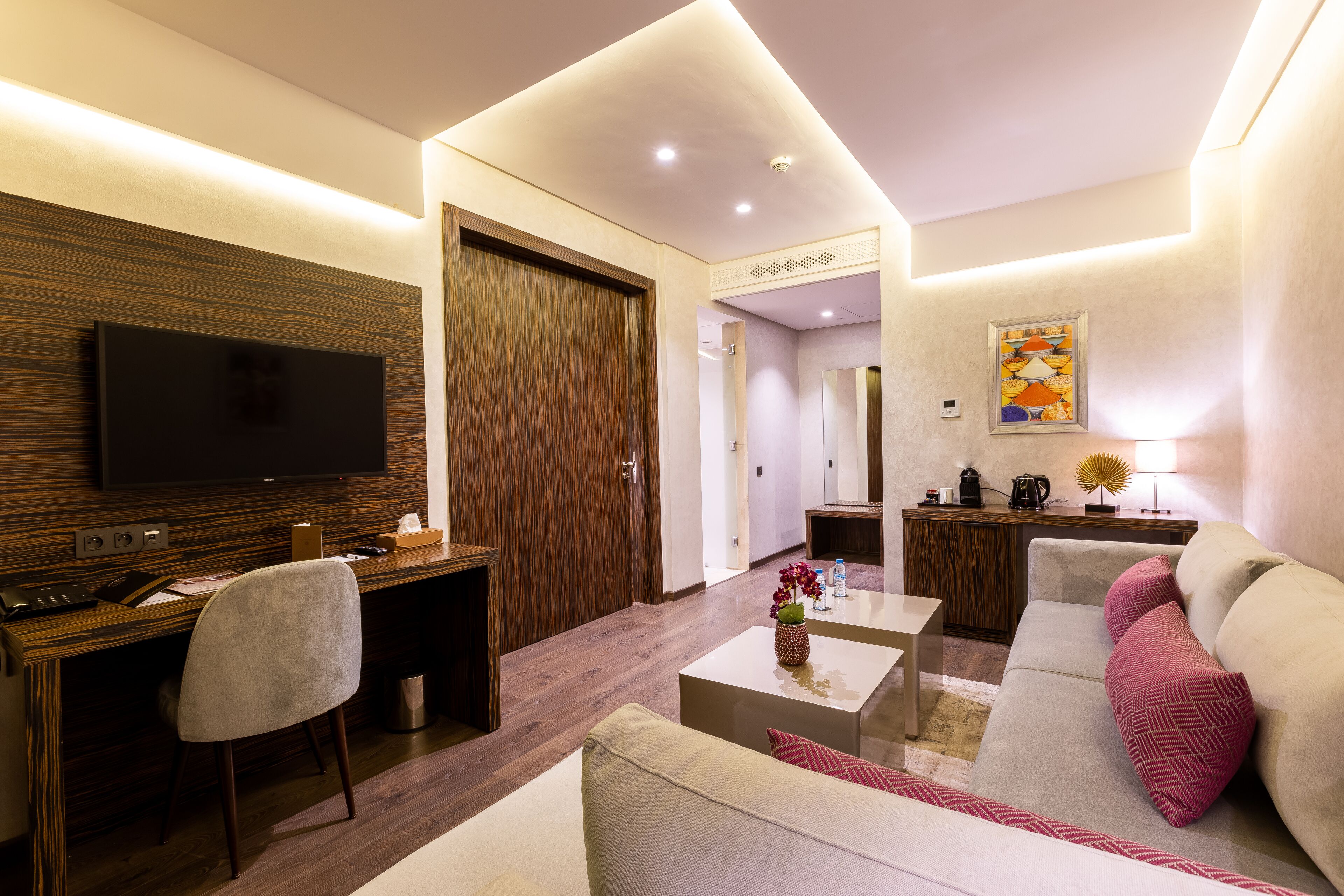 Una sala moderna con una televisión de pantalla plana, un escritorio de madera, un sofá y una mesa de centro.