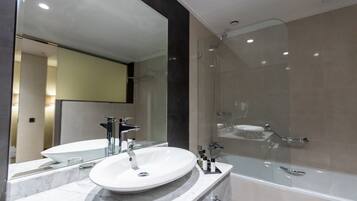 A modern bathroom with a white sink, a large mirror, and a glass-enclosed shower.