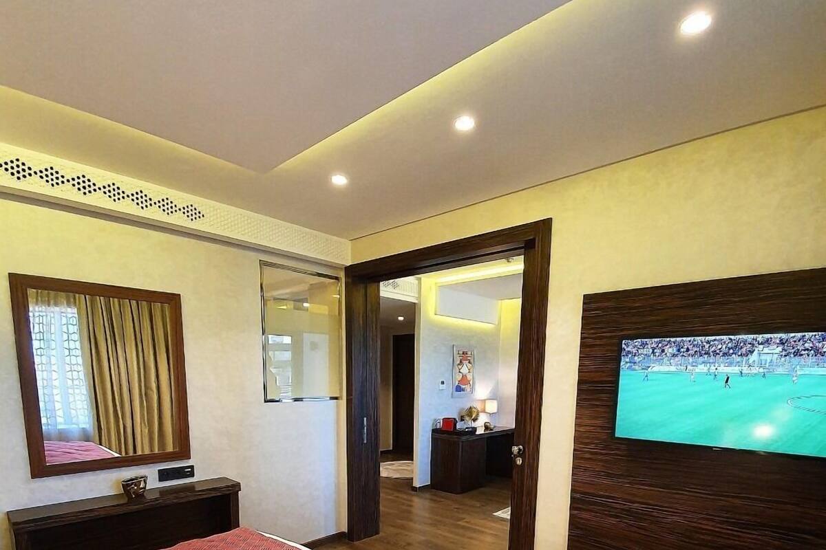 A hotel room with a large bed, a TV on the wall, and a mirror above the bed.