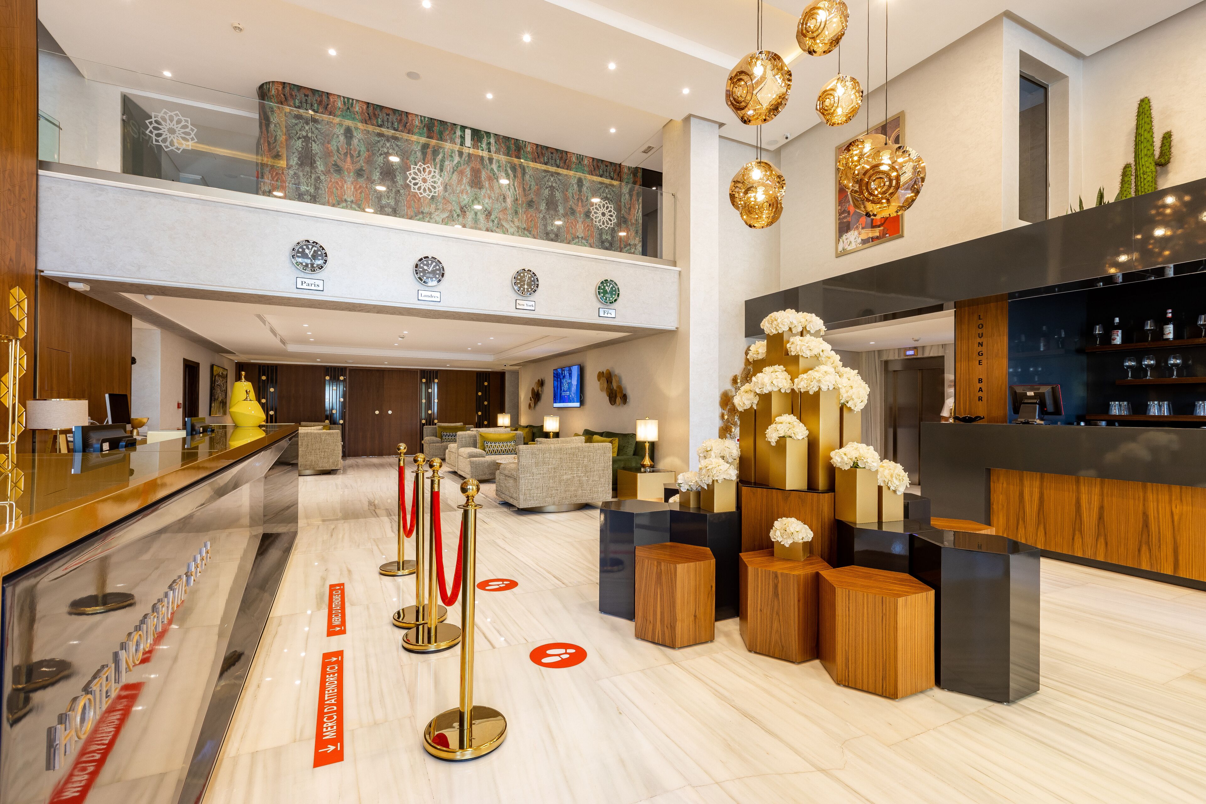 A modern hotel lobby with a reception desk, seating area, and a bar.