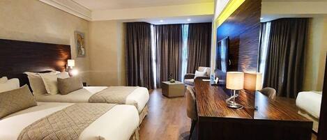 A hotel room with two beds, a desk, a chair, and a large mirror.