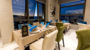 A restaurant with tables set for dining, large windows with city views, and a modern interior design. - Nour Plazza Fes (Fes)