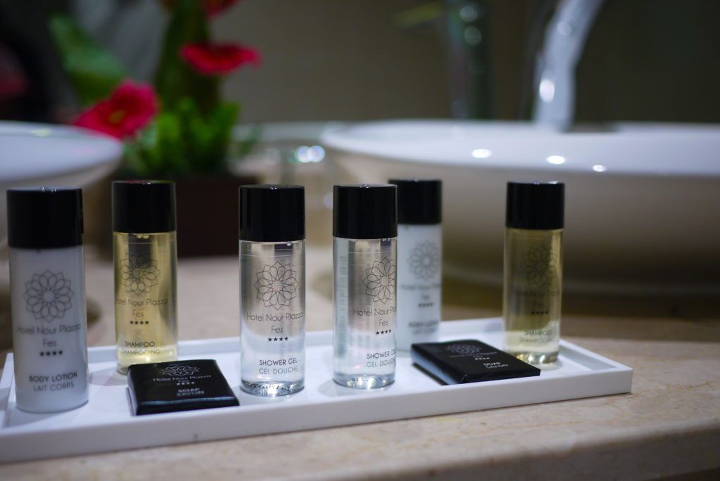 Une sélection de produits de toilette d’hôtel, comprenant une lotion pour le corps, un shampooing, un gel douche et un flacon de parfum.