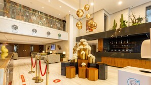 A hotel lobby with a reception desk, red velvet ropes, a bar area, and a decorative plant wall. - Nour Plazza Fes (Fes)