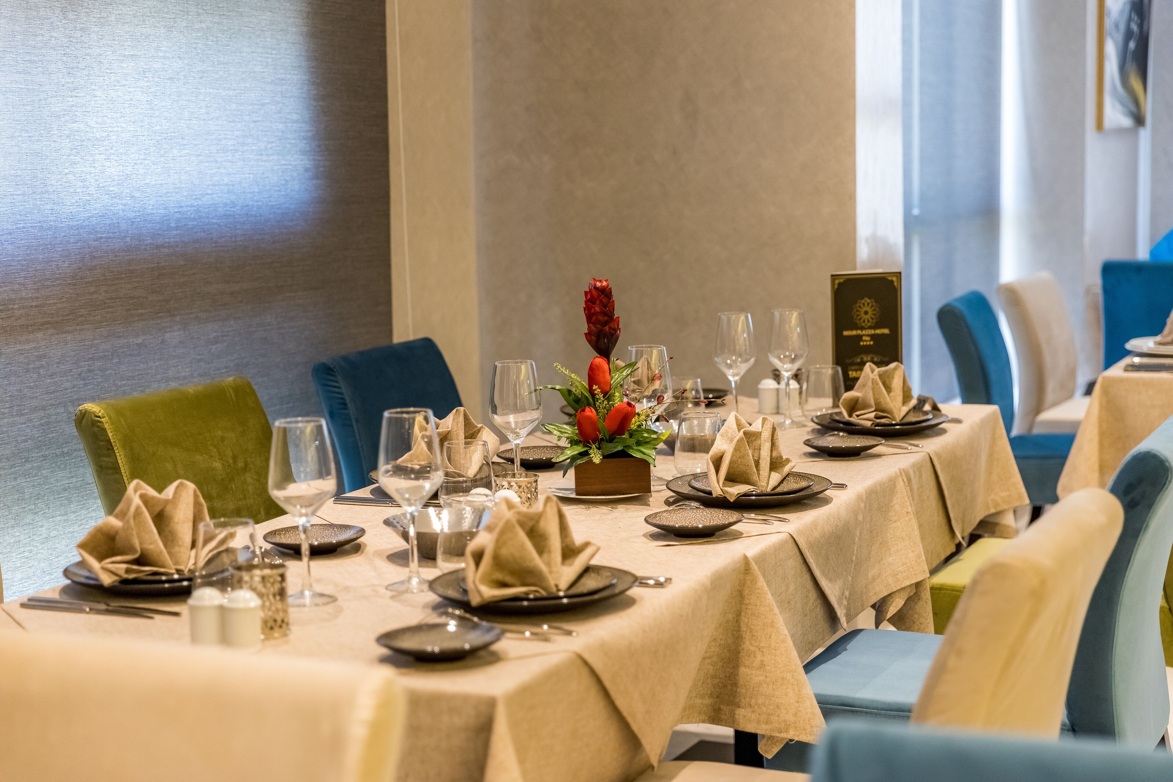 Una mesa de comedor dispuesta con platos, vasos y una decoración central.