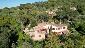 Una villa en la ladera con fachada de piedra, múltiples ventanas y un balcón.